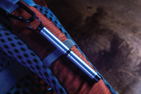 Fisher Backpacker Space Pen lifestyle image attached to a bag strap